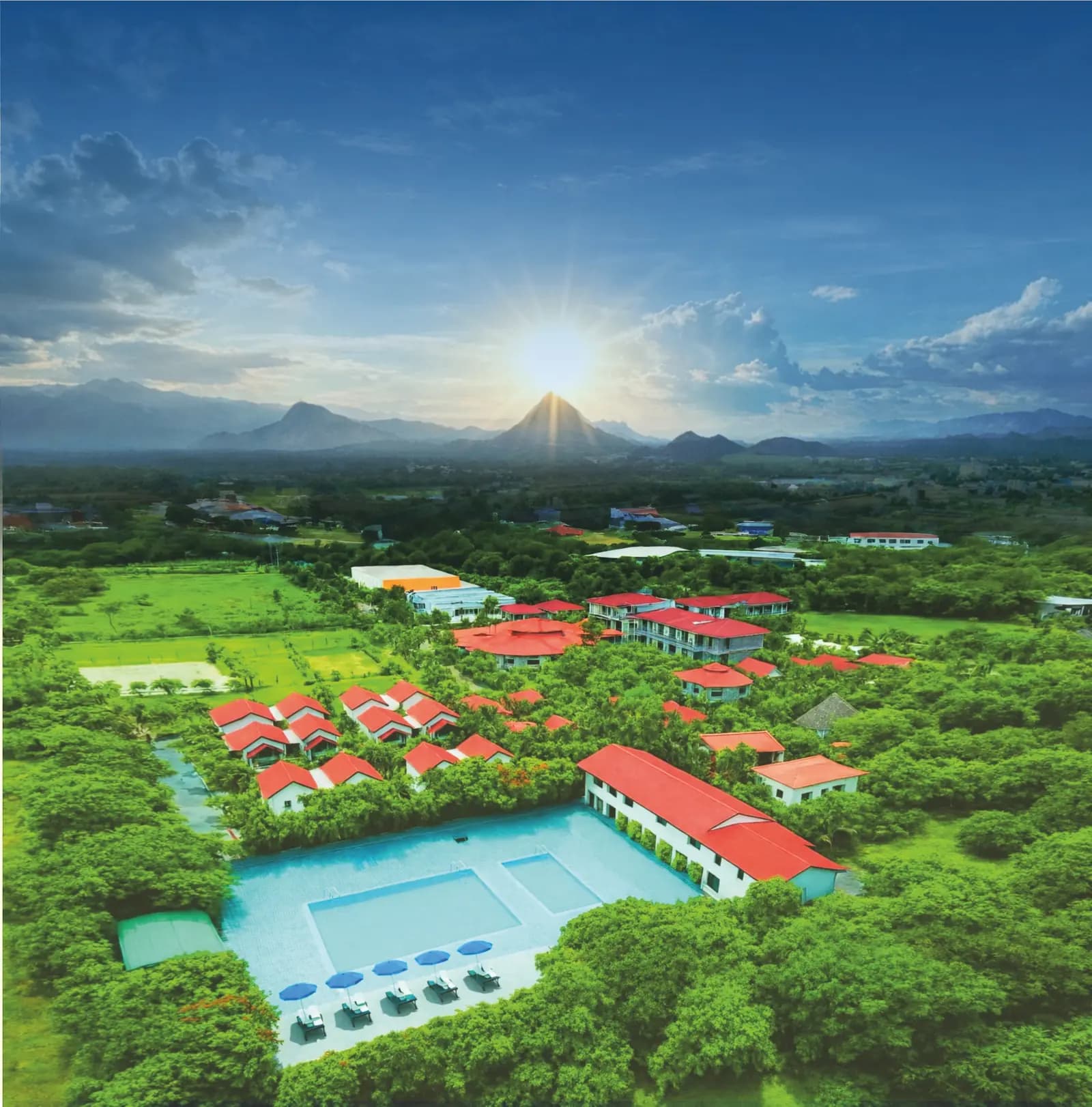 Aerial view at sunrise of a red-roofed Ayurveda resort with a pool near Mount Abu, Rajasthan