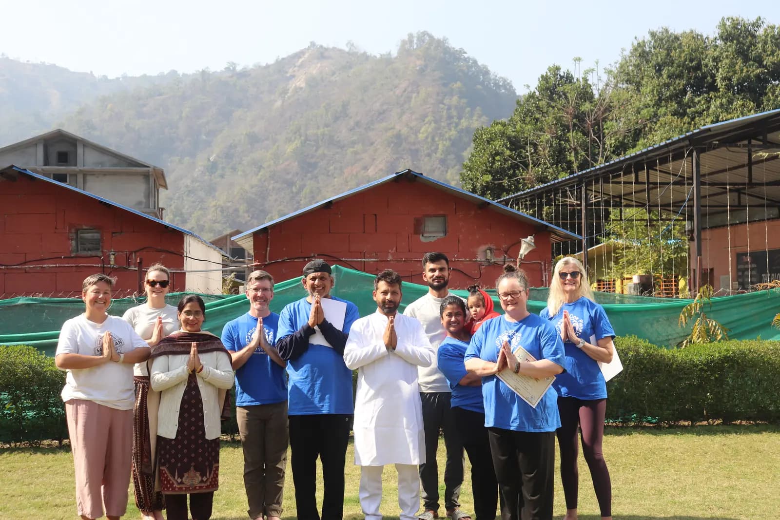 Students seated in a circle on a lawn outside cottages during a course in Rishikesh