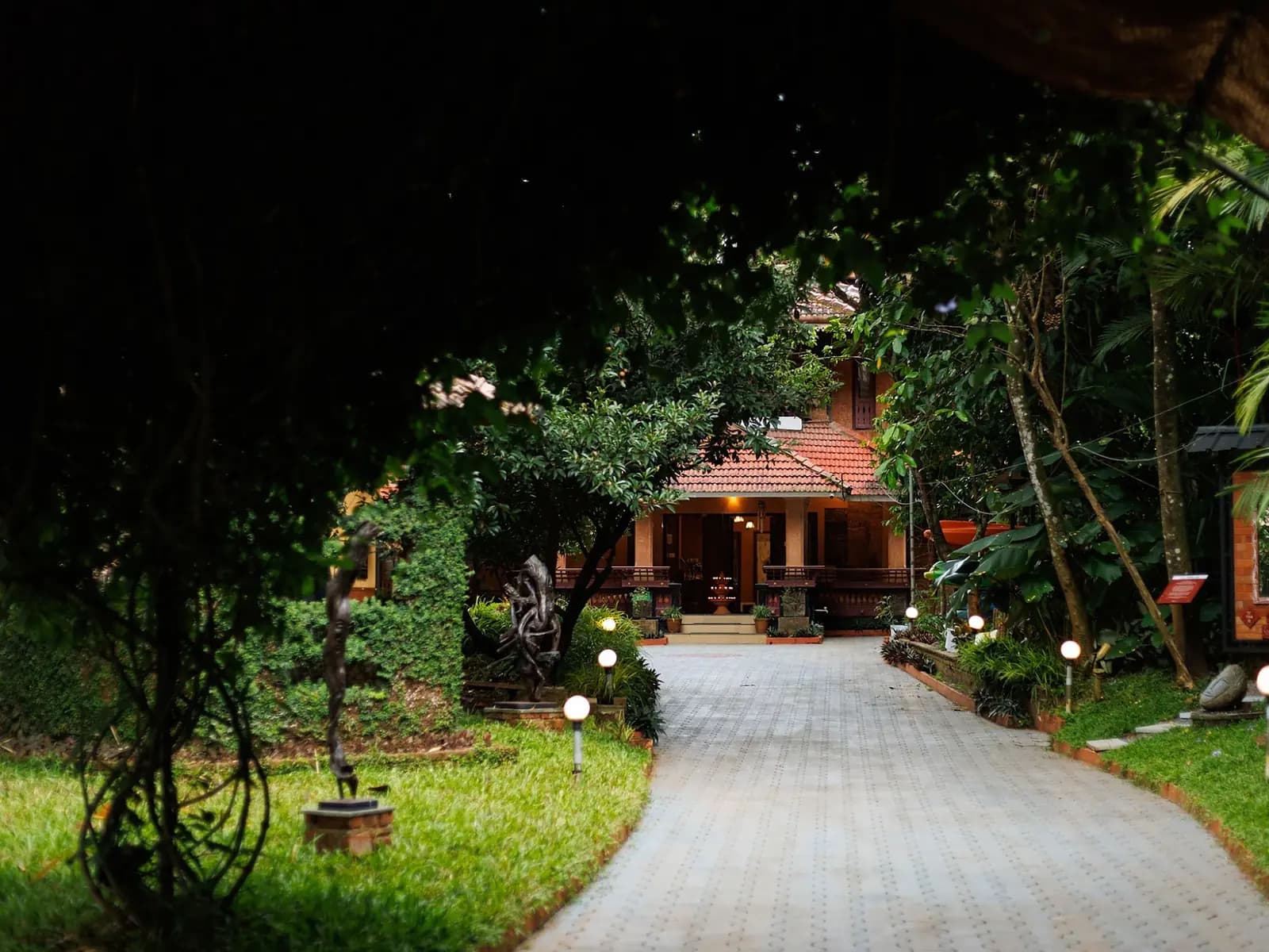 Lamp-lit garden path leading to a tiled Kerala house at an Ayurveda retreat near Kochi