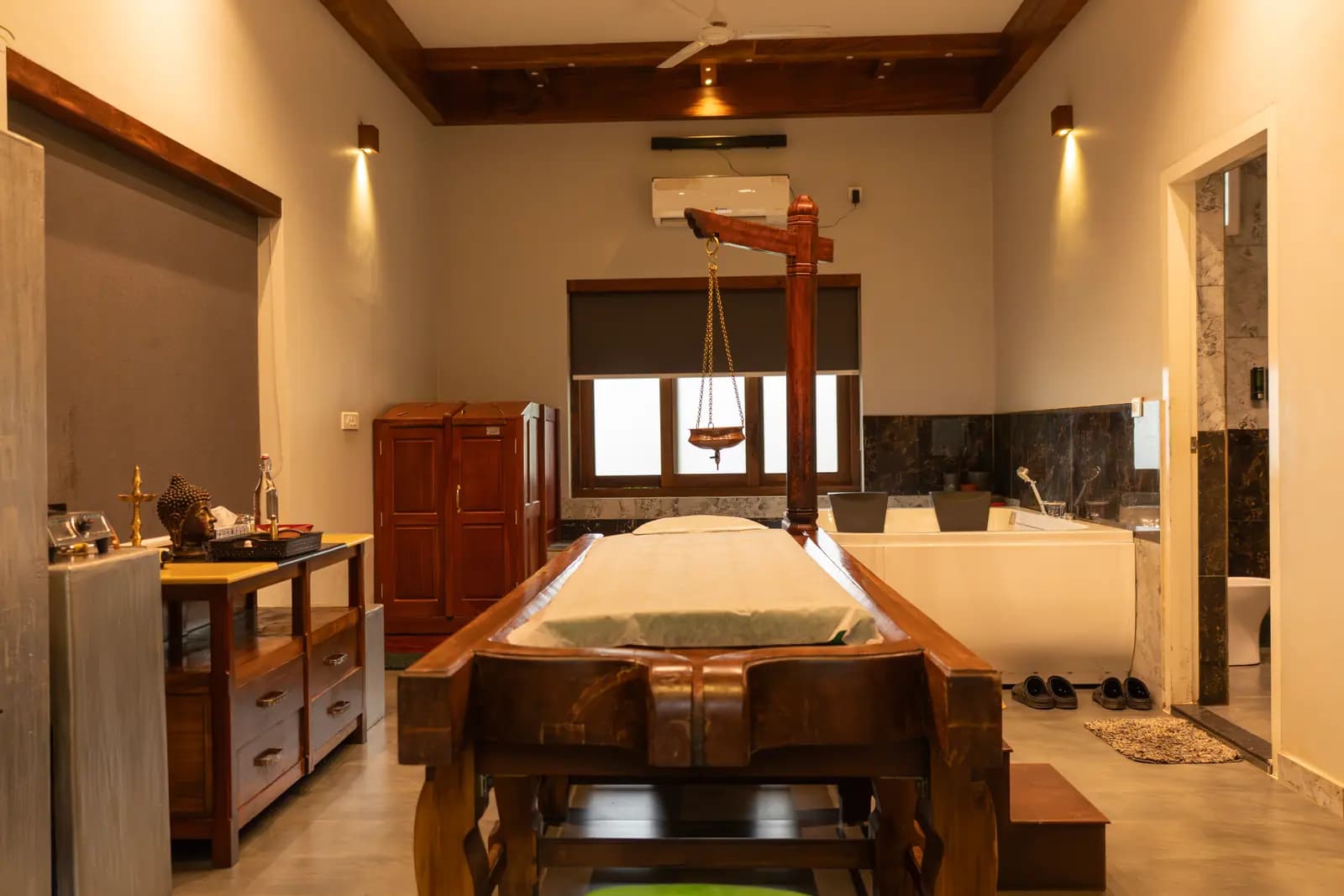 Ayurveda therapy room with a wooden treatment table and Shirodhara vessel at a retreat in Kerala