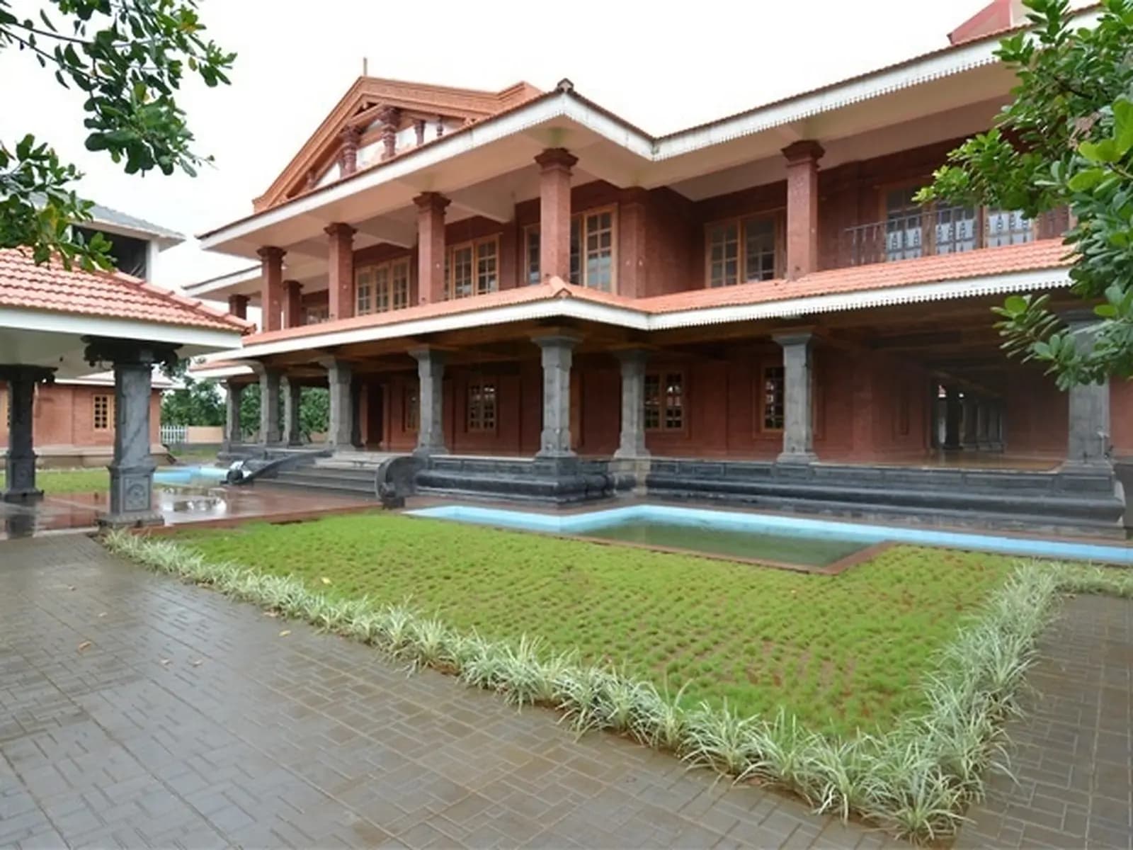 Kerala-style laterite building around a courtyard lawn at an Ayurveda centre near Panvel, Maharashtra