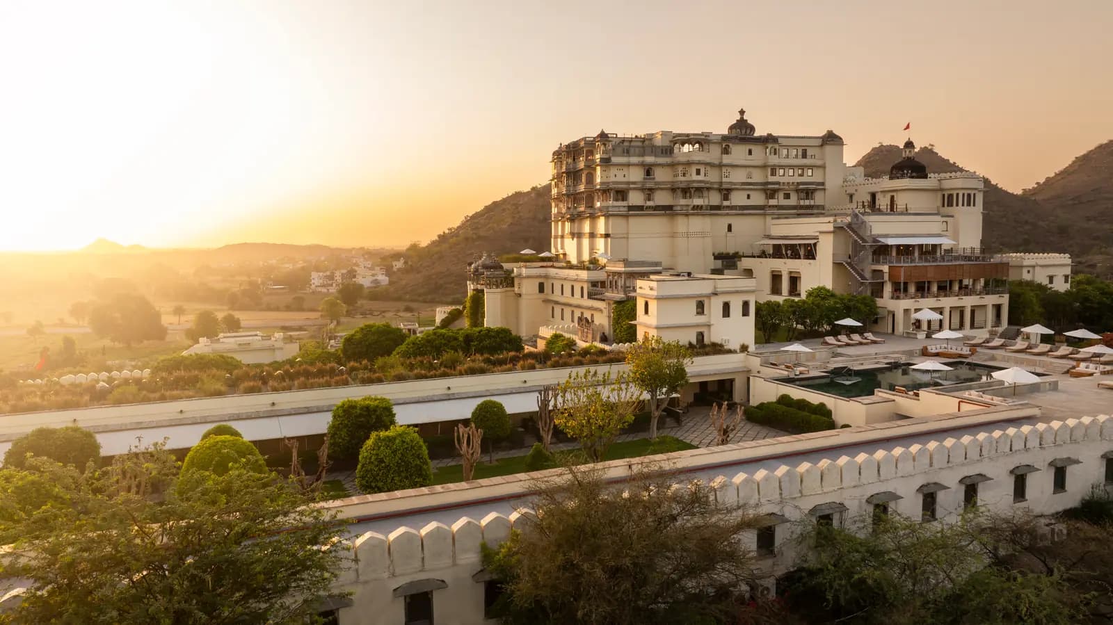 Restored hilltop fort palace above its gardens at sunset in the Aravalli hills near Udaipur