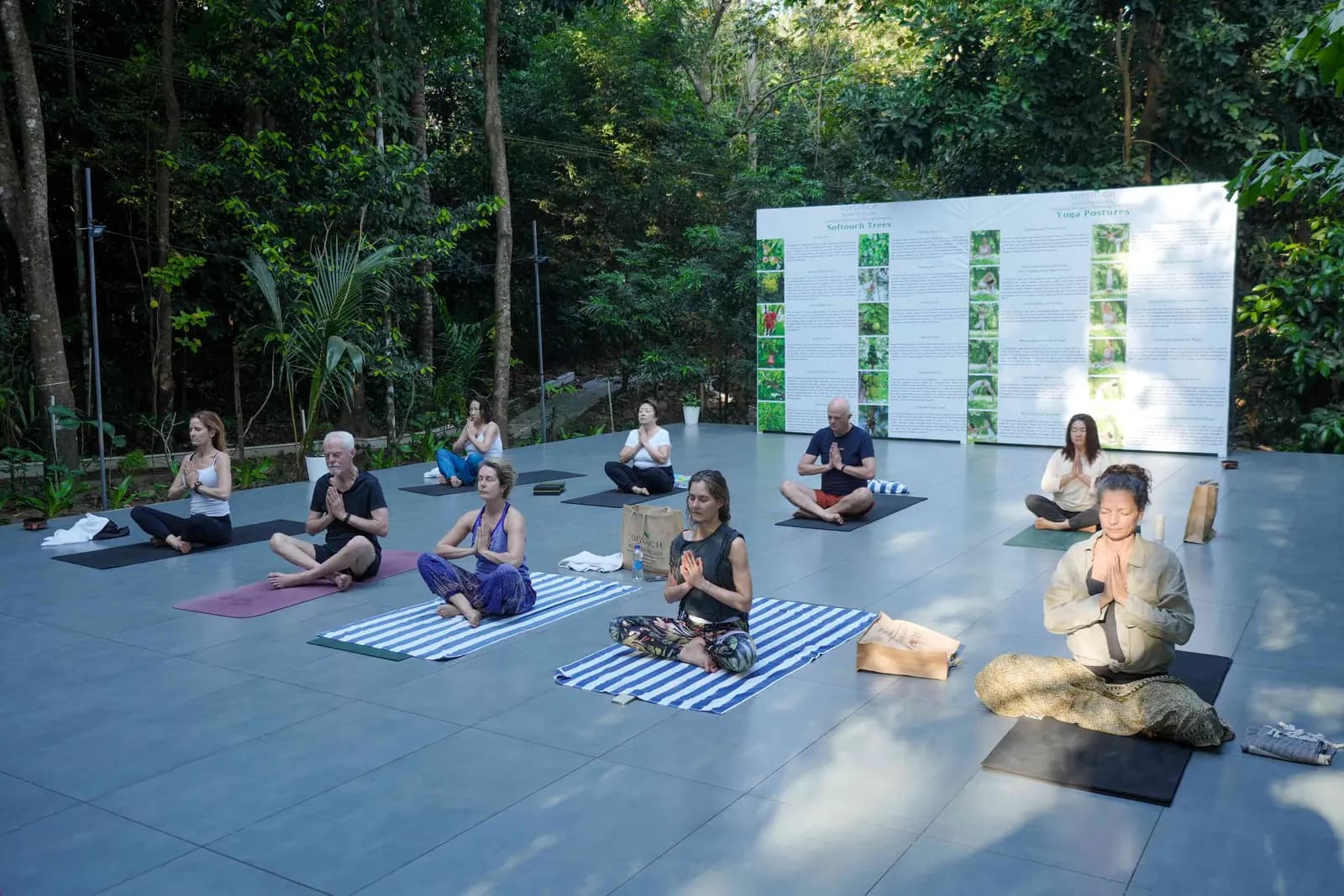 Guests meditating on an open-air yoga deck surrounded by forest at an Ayurveda retreat in Kerala